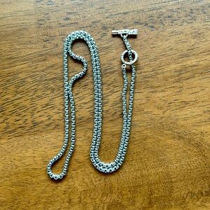 Silver colored lariat necklace with a pistol on the end